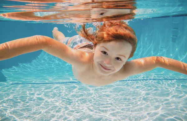 Divertido retrato facial de niño nadando y buceando bajo el agua con diversión en la piscina. Niño en el agua nadando bajo el agua y sonriendo. Los niños nadan bajo el agua. Cara divertida de los niños. — Foto de Stock
