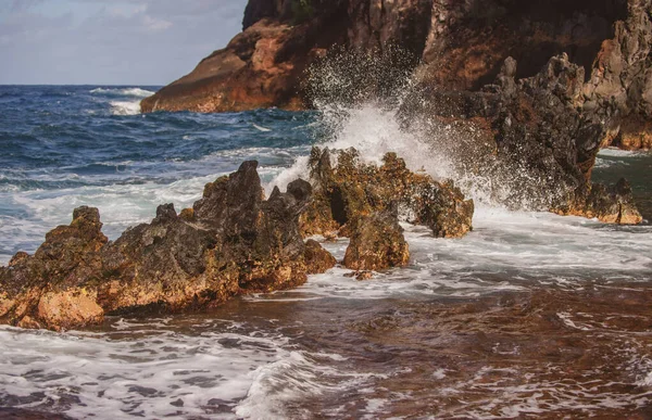 O mar colide com as pedras e areia de uma praia. ondas do mar linha de chicote impacto rocha. — Fotografia de Stock