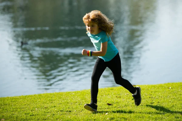 Barnpojken springer utomhus. Barnjoggare som springer i naturen. Morgonjoggar. Aktiva friska barn livsstil. Morgon löpning med barn. — Stockfoto