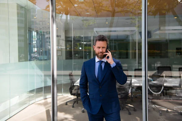 Affärsman pratar i telefon. Porträtt av glad Affärsman kontorsarbetare talar på mobiltelefon när du står nära moderna kontor. — Stockfoto