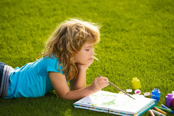 Målning av barn konst. Barn pojke målning med färger färg och pensel i park utomhus. — Stockfoto