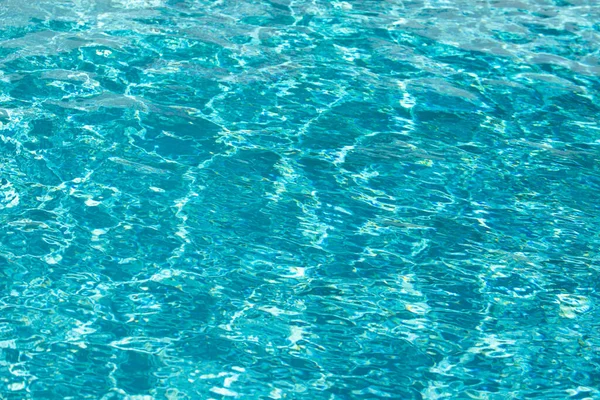 Yüzme havuzundaki mavi suyun arka planında güneş yansıması, havuzda dalgalı su dalgaları. Temiz su arkaplanı.