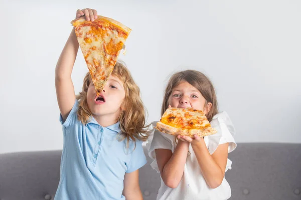 Hija feliz e hijo comiendo pizza. Los niños disfrutan y se divierten con el almuerzo juntos en casa. Lindos niños divertidos niña y niño comiendo sabrosa pizza. — Foto de Stock