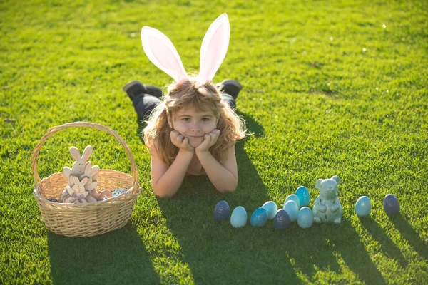 Vrolijk Pasen. Kind met paaseieren en konijnenoren op gras. Gelukkige Pasen kinderen gezicht. — Stockfoto