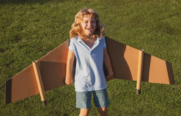 Leende barn som flyger i flygplan tillverkade av pappvingar. Dröm, fantasi, lycklig barndom. Resor och sommar semester koncept. — Stockfoto