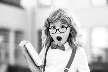 İlkokuldan bir çocuk. Gözlüklü mutlu çocuk ilk kez okula gidiyor. Okul çantası ve kitabı olan bir çocuk. Okula geri dön..