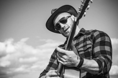 Gitarlı adam. Güneş gözlüğü takan ve arka planda gitar çalan yakışıklı bir genç. Kovboy adamlar. Batı kampı.