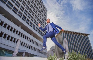 İşadamı koşuyor, işe gitmek için acele ediyor. Sokaklarda zıplarken tam boy genç iş adamı..