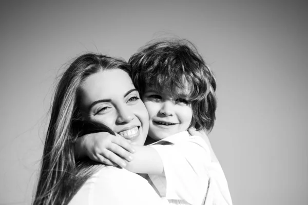 Lykkelig familie utendørs. Morsrollen. Sønn, omfavn mor. En ung smilende familie med barn. Unger elsker og klemmer mamma. Smil med ansiktet. Mødrenes dag. – stockfoto