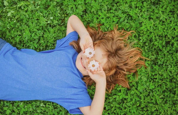 Gelukkig kind liggend op groen gras buiten in het voorjaarspark. — Stockfoto