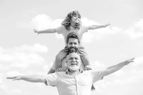 Generační rodina. Otec, syn a dědeček šťastní multi-genační rodina se zvednutýma rukama nebo otevřenou náručí létající na obloze. — Stock fotografie