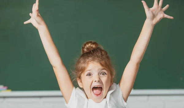 Cara menina da escola animado com expressão surpreendente contra quadro negro. — Fotografia de Stock