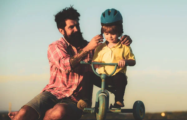 Ayuda a los niños a explorar el mundo. Feliz familia amorosa Padre e hijo. Niño pequeño con casco mientras aprende a montar en bicicleta con su papá. — Foto de Stock