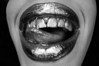 Seksi dilli. Şehvetli yalama. Lüks altın dudaklar makyaj. Altın rujlu altın dudaklar. Seksi kızın dudaklarında altın boya. Şehvetli kadın ağzı, izole bir arka plan..