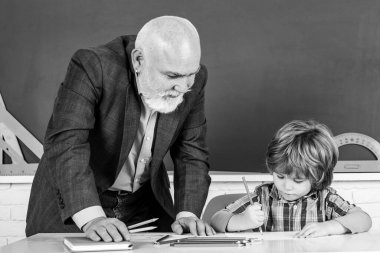 İlkokulun arka sınıfında son sınıf öğretmeni ve öğrencisi var. Okulda son sınıf öğretmeniyle ders alan çocuk..