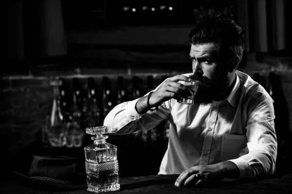 Homem com barba e bigode segura bebida alcoólica no fundo do bar. Conceito de serviço e alcoolismo. — Fotografia de Stock