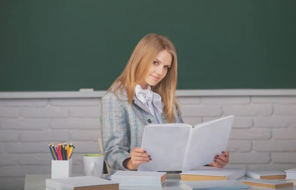 Kvinnlig student håller bok på lektionsföreläsning i klassrum på gymnasiet eller högskolan. — Stockfoto