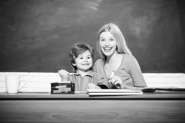Lachende jonge leraar en kleine student schooljongen in een klaslokaal. — Stockfoto