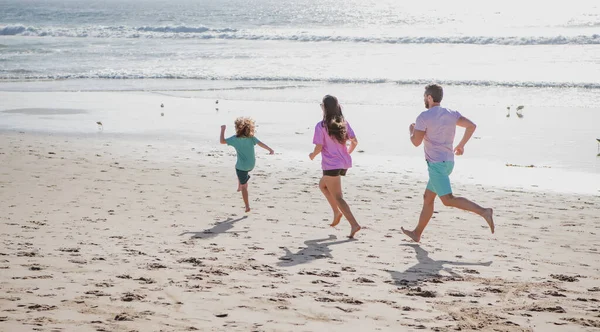 Familia corriendo en una playa de arena. Concepto de jogging familiar amistoso al aire libre. Padres activos y personas actividad al aire libre en vacaciones tropicales de verano con niños. —  Fotos de Stock