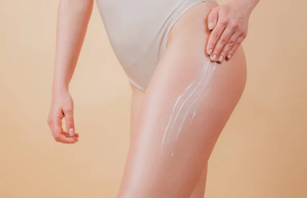 Creme cosmético na perna da mulher com pele macia limpa. Aplicando creme hidratante nas pernas. Cuidado corporal e conceito de salão de spa. — Fotografia de Stock