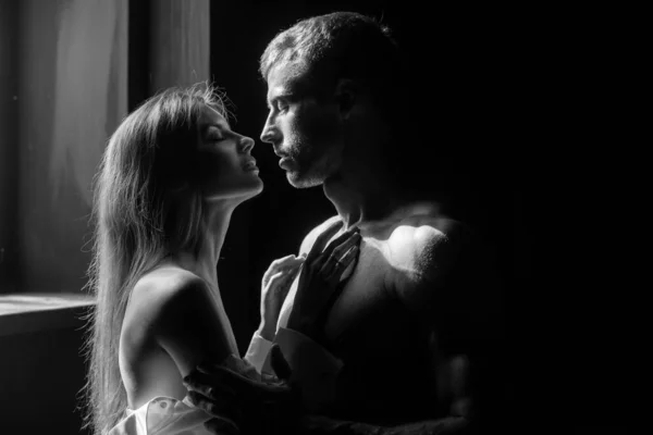 Romantisches verliebtes Paar schaut einander an, umarmt und küsst sich im Schlafzimmer auf schwarzem Hintergrund. — Stockfoto