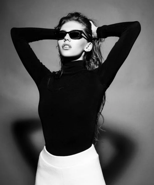 Sexy vrouw met een zwarte zonnebril. Portret van een sensueel meisje dat geïsoleerd op grijs kijkt. — Stockfoto