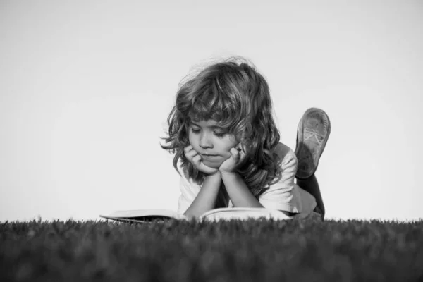 Niños aventura, libertad y niños despreocupados. Lindo niño leyendo libro fuera en la hierba. —  Fotos de Stock