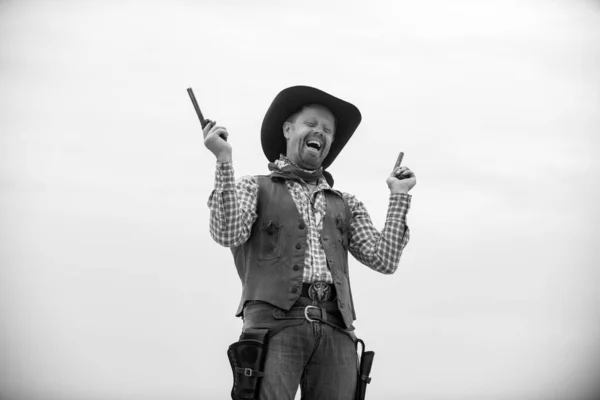 Wollte Western. Glücklich lustiger Cowboy mit Waffe. Amerikanischer Bandit, westlicher Mann mit Hut. Westen und Waffen. — Stockfoto