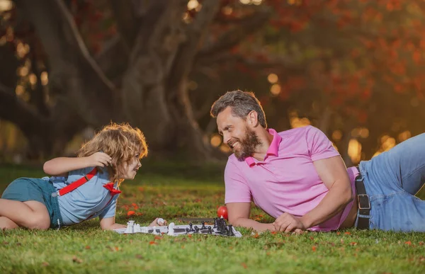 Otec a syn hrají šachy a tráví spolu čas venku. Inteligentní dítě, chytré děti. — Stock fotografie