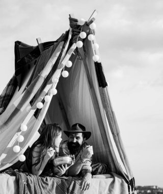 Kamp çadırının yanında yemek yiyen genç bir çift. Birbirine aşık kamp çifti. Sevgili turistler doğada rahatlar. Aşıklarla kamp gezisi. Kampta aşıklarla kahvaltı.