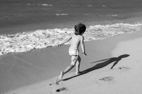 Ragazzo che gioca in spiaggia durante le vacanze estive. Bambini nella natura con bellissimo mare, sabbia e blu che scorre nell'acqua del mare. — Foto Stock