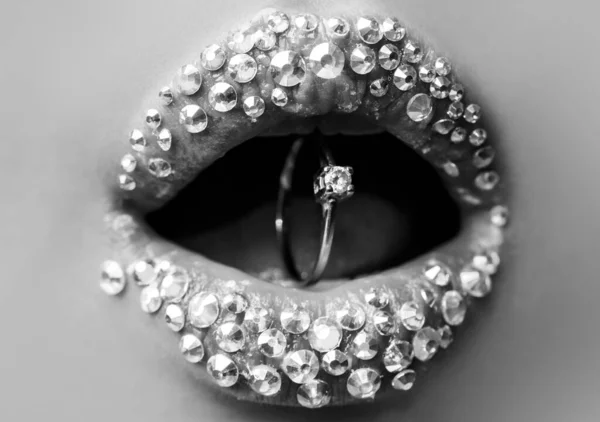 Prsten s diamantem v puse. Červené rty s prstenem. Detailní záběr krásných ženských rtů. Ústa se svatebním zlatým diamantovým prstenem. Šperky. Rty s diamantovými šperky. — Stock fotografie