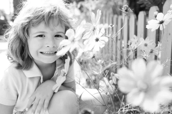 Primer plano retrato de un niño lindo con flores de verano al aire libre. Concepto de infancia. —  Fotos de Stock