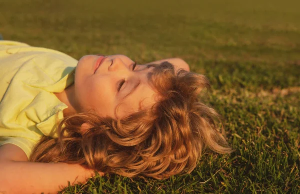 Porträtt av en glad leende pojke som leker på gräsplan. Ungar drömmer. — Stockfoto