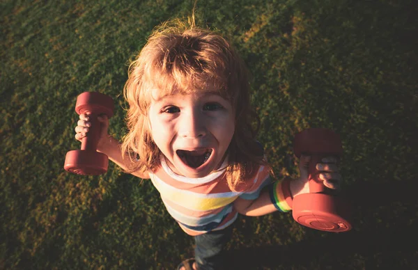 Actividade infantil. Miúdo engraçado com halteres. Ângulo largo. — Fotografia de Stock