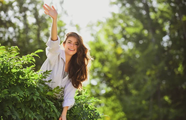 Vänlig kvinna säger hej hälsningar på naturen bakgrund i sommar eller vår park. — Stockfoto