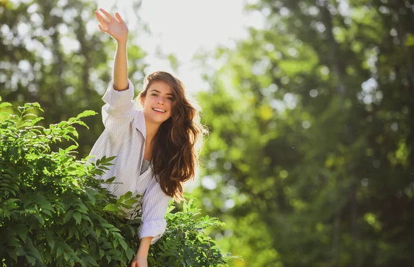 Mujer amigable saludos de saludo en el fondo de la naturaleza en verano o parque de primavera. — Foto de Stock