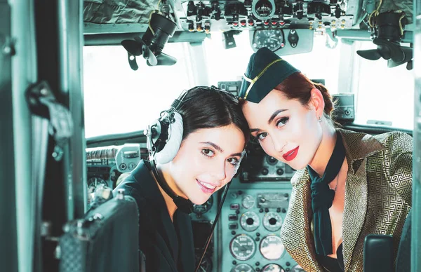 Dvě pilotky sedí v kabině moderního letadla. Usmívající se letuška v letadle. Portrét atraktivní ženské školící pilotky s náhlavní soupravou připravující se k letu. Šťastní piloti. — Stock fotografie