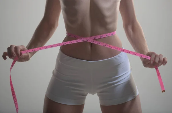 Uma jovem mulher a medir a cintura. Feminino ajuste corpo magro. — Fotografia de Stock