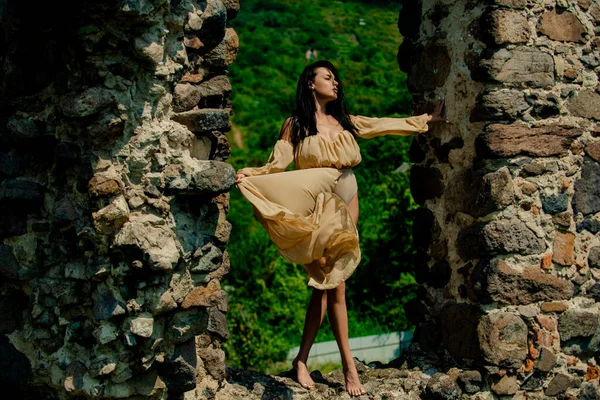 Mulher bonita vestindo roupas de primavera na moda. Mulher, modelo de moda na fortaleza, parede velha das pedras do castelo. Retrato do modelo de moda em vestido da moda. — Fotografia de Stock