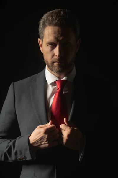 Studioporträt eines seriösen Geschäftsmannes, der Anzug und Krawatte trägt und nachdenklich schaut, während er vor isoliertem, dunklem Hintergrund steht. Ernsthaftes Geschäftsmann-Gesicht. — Stockfoto