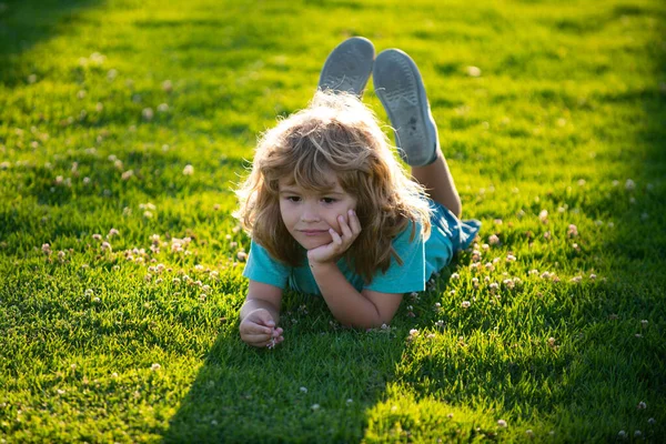 Retrato de un niño sonriente acostado sobre hierba verde. sonriente chico tener divertido al aire libre en primavera jardín. —  Fotos de Stock