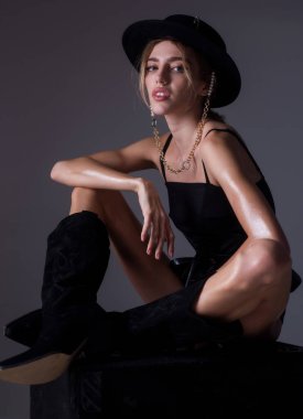 Şapka portresindeki yüksek model. Stüdyoda şık bir kadın moda elbisesi giyiyor. Güzel kız moda kıyafetleri giyer. Günlük kıyafet, moda tarzı..