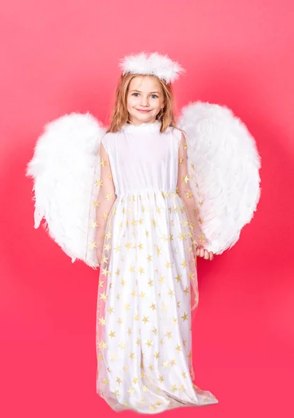 Angel kind met witte vleugels en engelen halo, Valentijnsdag. Angelic kids meisje, geïsoleerde rode studio achtergrond met kopieerruimte. — Stockfoto