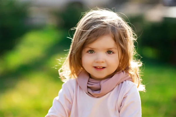 Barnet på det gröna gräset i sommarparken. Närbild av babyn. Lustigt litet barn på nära håll. Blond unge, leende känslomässigt ansikte. — Stockfoto