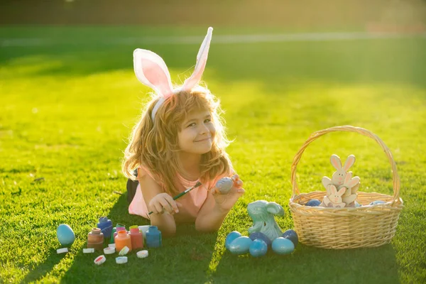 Gyerek fiú húsvéti tojással és nyuszifülekkel a szabadban. Vicces fiú, húsvéti nyuszi gyerekek. — Stock Fotó