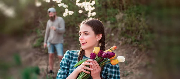 Spring woman face for banner. Young woman entrepreneur working in flower garden. Young woman holding tulips in the garden. — Stock Photo, Image
