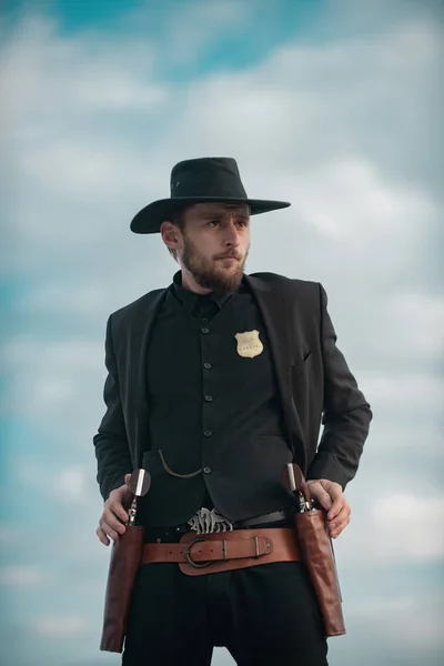 Sheriff in zwart pak en cowboyhoed. Man met wilde westelijke wapens, vintage pistoolrevolver en marshal munitie. US Marshals, Amerikaanse westerse sheriff. Wild westen met cowboy. — Stockfoto