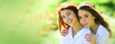 Açık havada kadın kız arkadaşlarla bahar pankartı. Parktaki güzel kadın. İki güzel kızıl kız. Neşeli kardeş, kavramı kucakla..