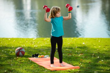Arka bahçede dambılları kaldıran komik çocuk. Eğitimdeki çocuklar.
